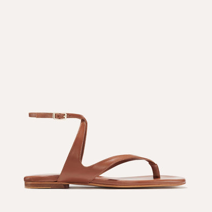 The Palermo Sandal - Saddle Nappa by Margaux is a brown leather flat with a minimalist design, featuring toe and curved upper straps, an ankle strap with buckle, and a cushioned insole for comfort—perfect for summer getaways.