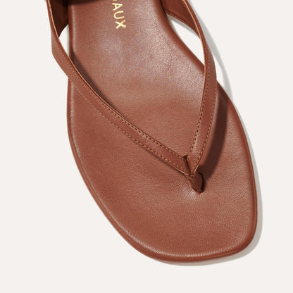 Close-up of The Palermo Sandal - Saddle Nappa by Margaux: a brown leather thong sandal with a single strap, toe loop, and cushioned insole—ideal for summer days and timeless getaway style.