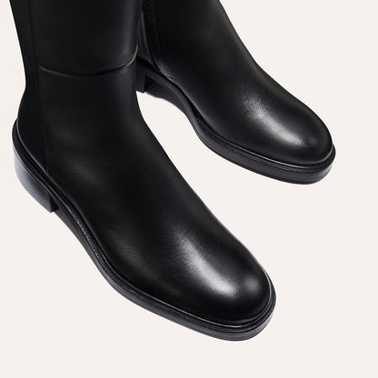 The City Boot - Black Calf by Margaux features sleek black leather with a smooth finish, low heels, and a classic silhouette, shown from above on a light background.