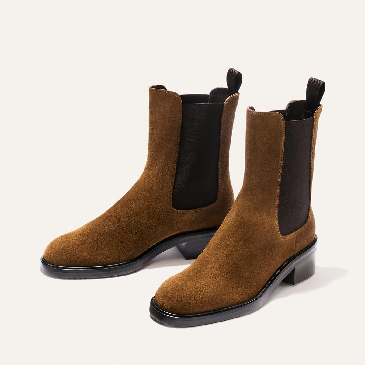 The City Chelsea Boot - Cedar Suede by Margaux, featuring brown suede uppers, black elastic side panels, and low black heels, is displayed on a light background.