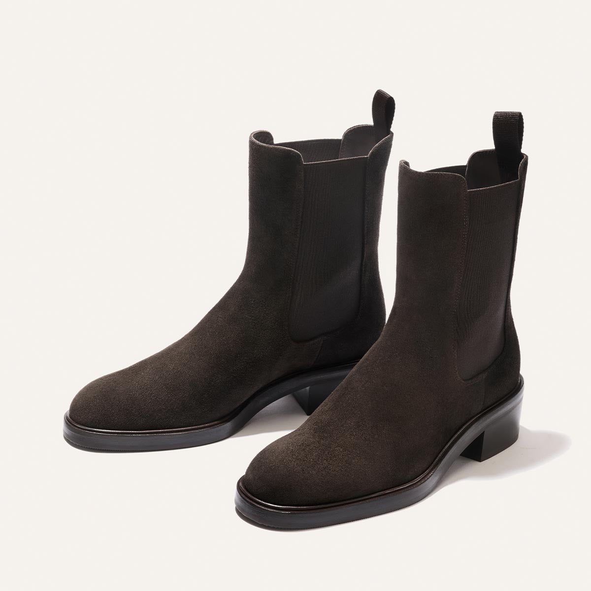 A pair of The City Chelsea Boot in Dark Chocolate Suede by Margaux, featuring elastic side panels and pull tabs, displayed on a light background.
