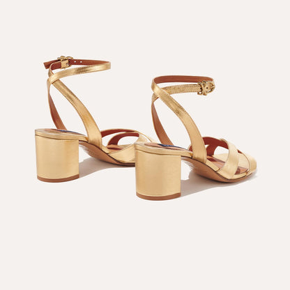 The City Sandal in metallic Gold Nappa, featuring carefully placed straps, and adjustable ankle strap and a comfortable 2.5-inch block heel.