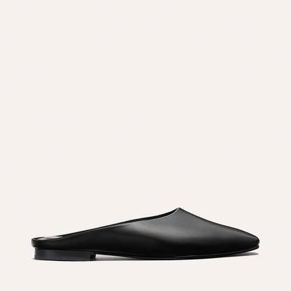 The Clara - Black Calf by Margaux is a black leather slip-on mule with a flat sole, shown in side profile against a plain light background.