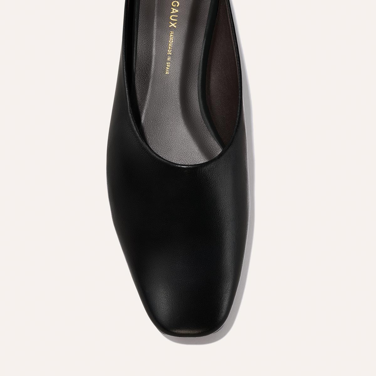 A close-up top view of Margaux’s The Clara - Black Calf shoe reveals its square toe, black leather upper, and part of the insole.