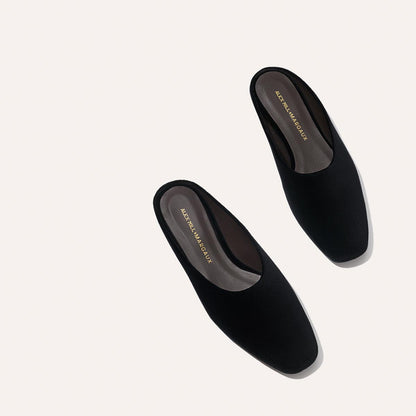 A pair of black velvet slip-on mules, “Alex Mill x Margaux: The Clara - Black Velvet” by Margaux, featuring a square toe and flat sole, displayed on a light background—versatile style for any look.