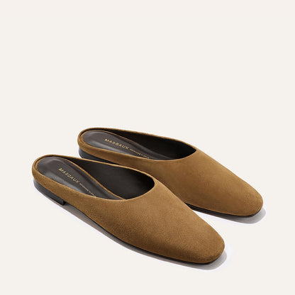 A pair of The Clara - Cedar Suede slip-on flats by Margaux, featuring brown suede, closed rounded toes, low heels, and branded insoles, displayed against a light background.