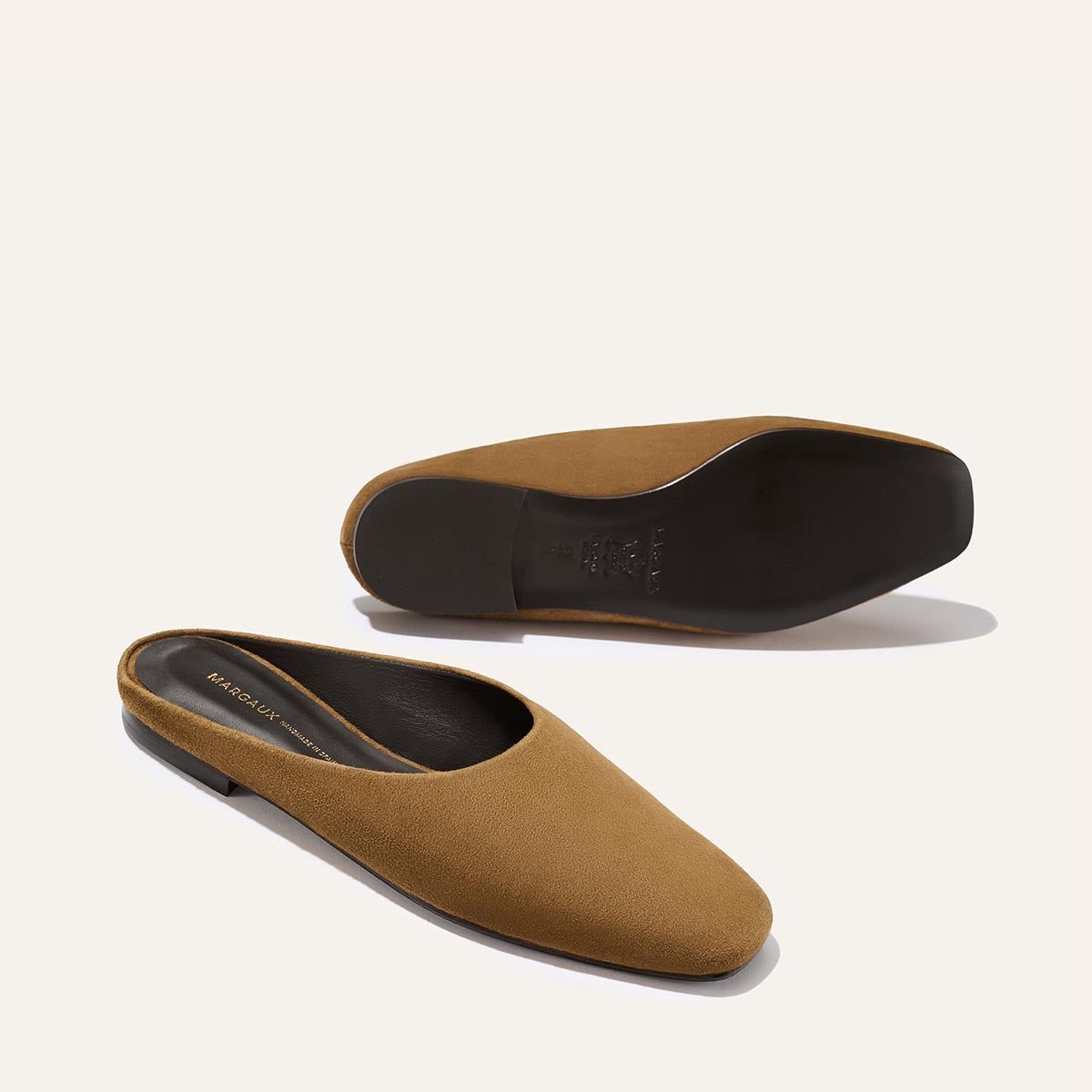 The Clara - Cedar Suede by Margaux: brown suede slip-on loafers with closed toes and black soles, shown from the side and bottom on a plain light background.