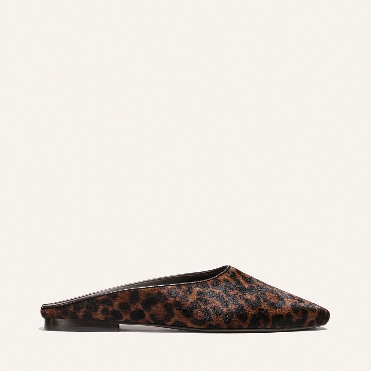 The Clara - Chocolate Leopard Haircalf by Margaux is a flat mule shoe featuring a brown and black leopard print pattern, photographed from the side against a plain white background, highlighting its versatile style.