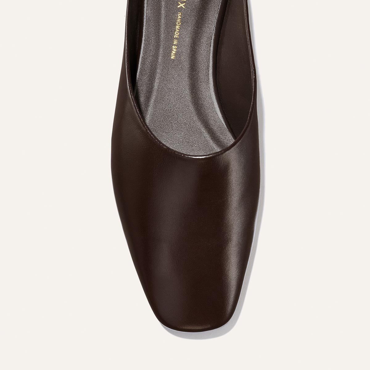 A top view of The Clara - Coffee Calf by Margaux highlights its do-it-all style and slipper-like silhouette, featuring a dark brown leather upper and square toe, set against a light background.