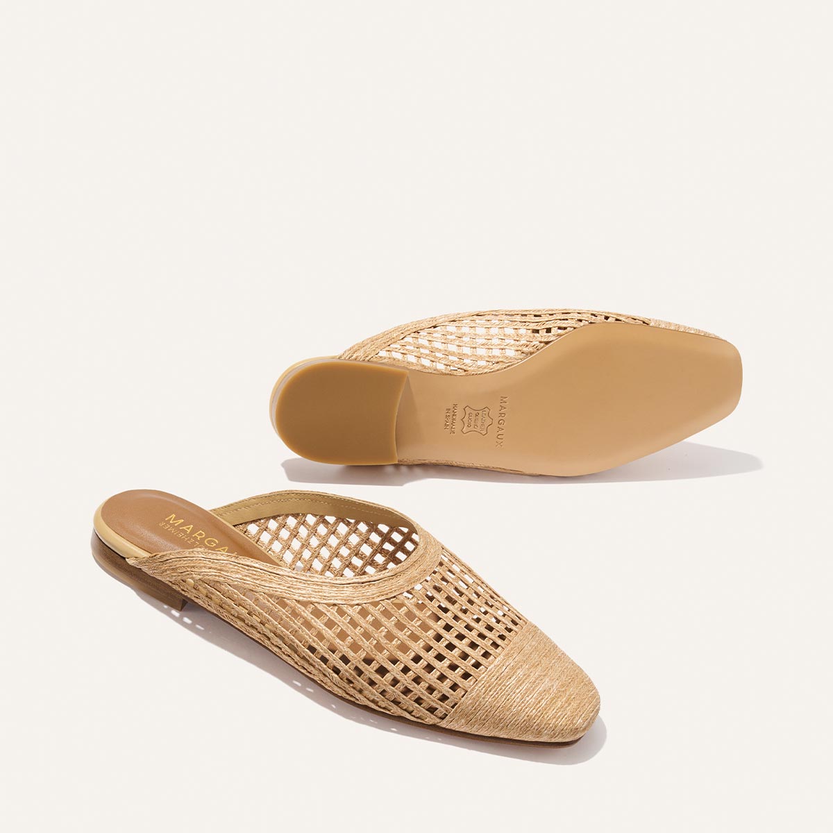 Pair of woven beige slippers on a white background