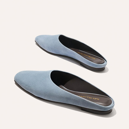 The Margaux Alex Mill x Margaux: The Clara - Slate Blue Suede features closed toes, brown insoles, and black soles—a stylish, versatile slip-on flat shown on a light background.