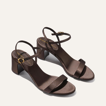 The Cleo Sandal - Espresso Satin by Margaux: a pair of brown, open-toe block heel sandals with ankle straps and gold buckle accents, shown on a light background.