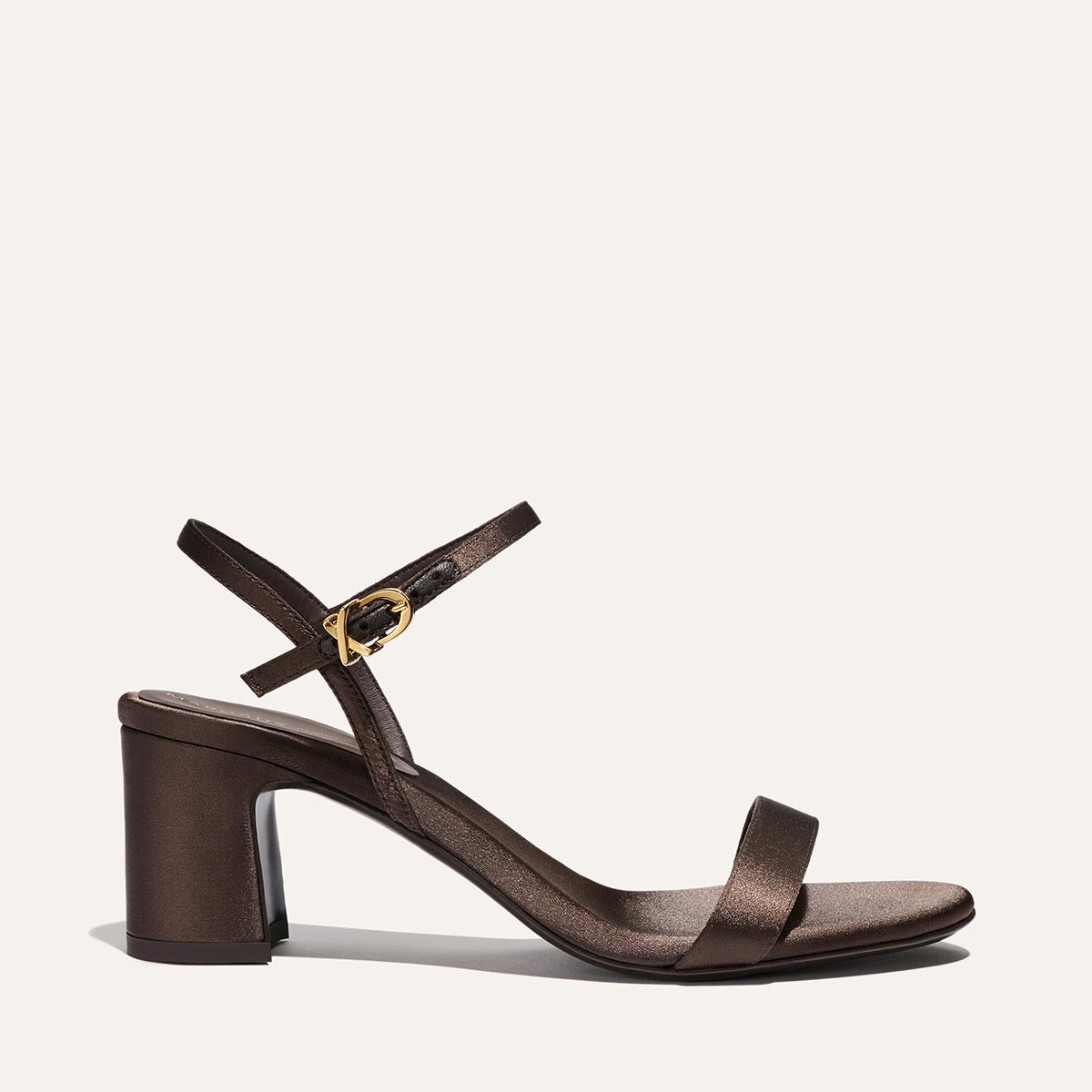 The Cleo Sandal - Espresso Satin by Margaux features a brown satin finish, open toe, block heel, slim toe strap, and an ankle strap with a gold buckle, shown against a plain light background.