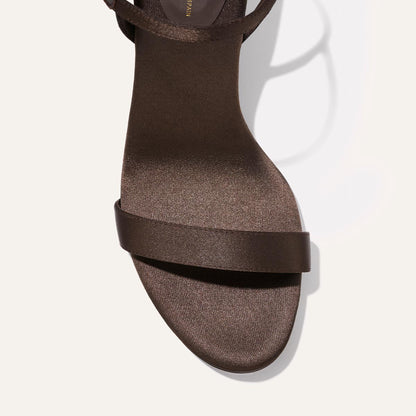 A close-up top view of The Cleo Sandal in Espresso Satin by Margaux, featuring a single toe strap and an ankle strap, displayed against a plain light background.