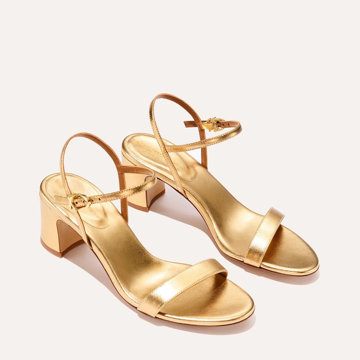 The Cleo Sandal in shiny Gold Nappa, a comfortable 2.5-inch heeled sandal with a sleek strap across the toes and perfectly placed instep strap.