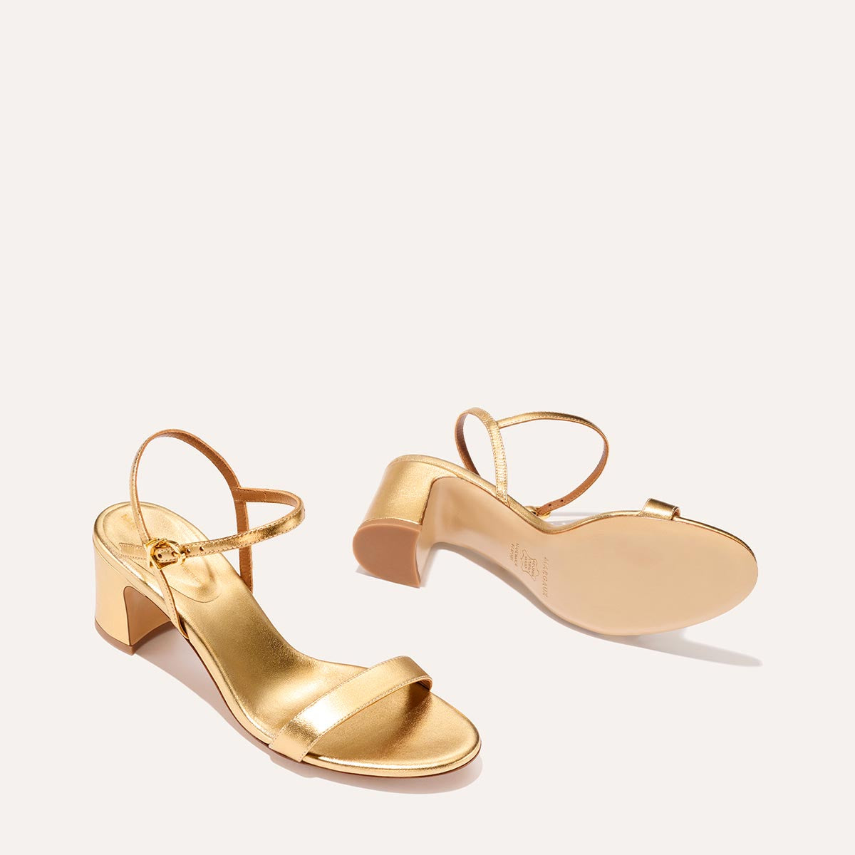 The Cleo Sandal in shiny Gold Nappa, a comfortable 2.5-inch heeled sandal with a sleek strap across the toes and perfectly placed instep strap.