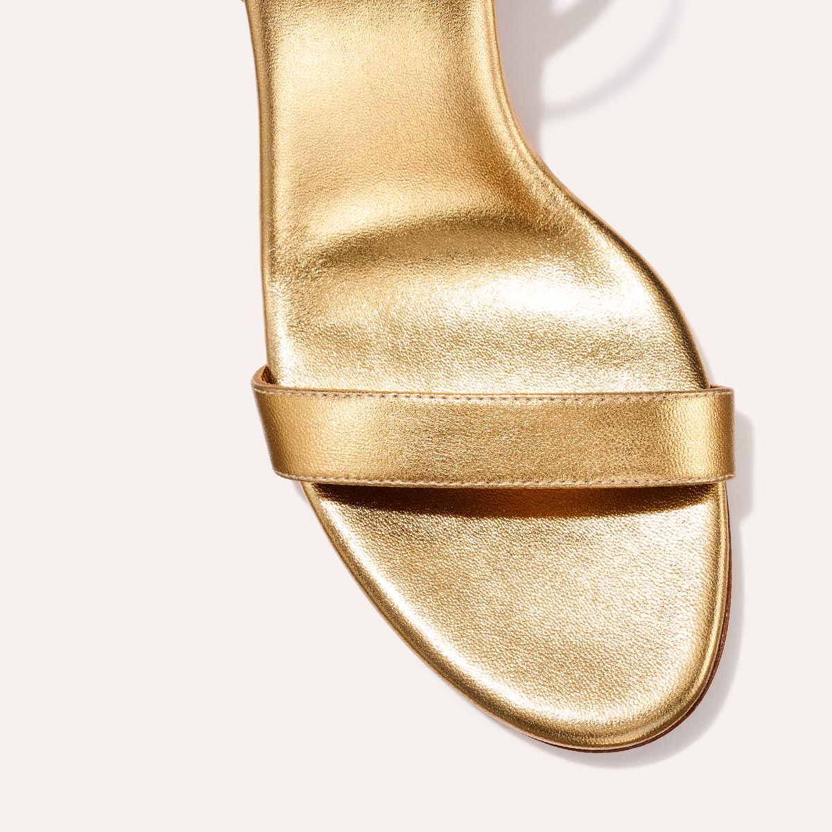 The Cleo Sandal in shiny Gold Nappa, a comfortable 2.5-inch heeled sandal with a sleek strap across the toes and perfectly placed instep strap.