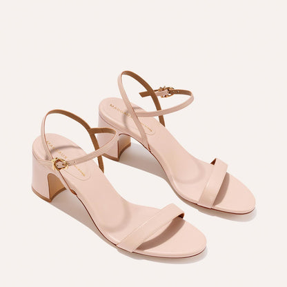 The Cleo Sandal - Petal Nappa by Margaux features a blush pink, open-toe block heel with thin ankle straps and a minimalist design, showcased on a plain light background.