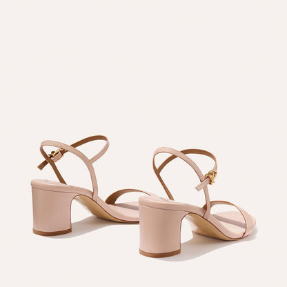 The Cleo Sandal - Petal Nappa by Margaux features light pink, open-toe design with mid-height comfortable heels and thin ankle straps with gold buckles, displayed on a plain light background.