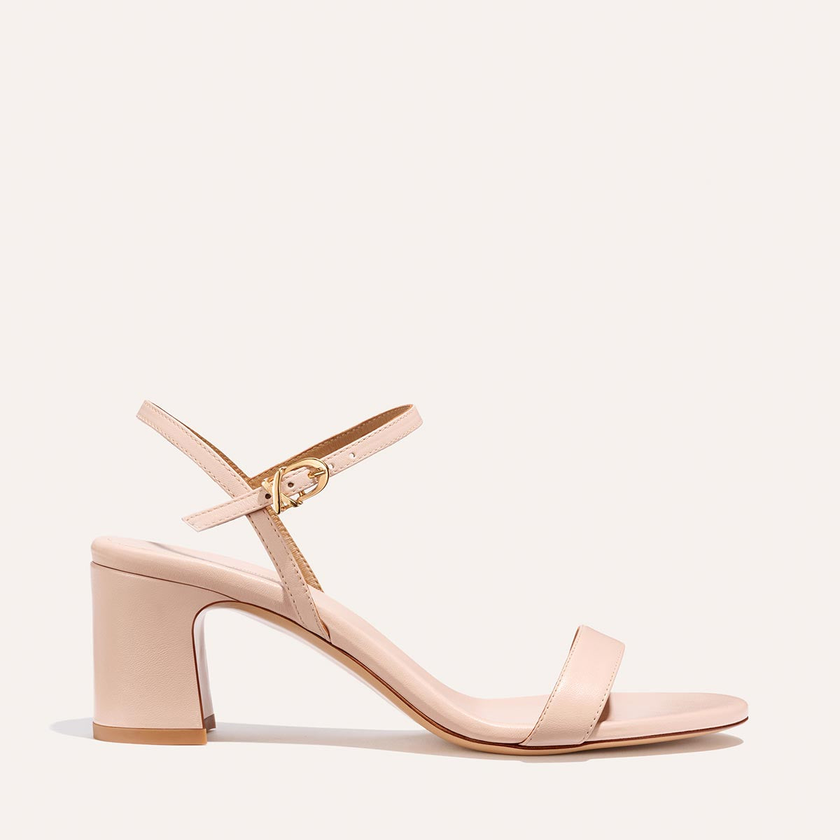 The Cleo Sandal - Petal Nappa by Margaux is a nude, open-toe block heel featuring a single toe strap and slim ankle strap with a gold buckle, shown against a plain light background.