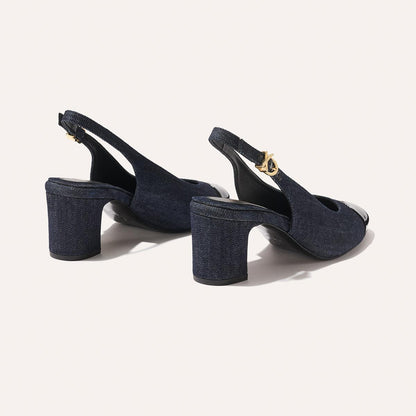 The Cluny Slingback by margaux-development features indigo denim and patent, open toes, block heels, and gold buckle ankle straps—an elegant staple—shown on a light background.