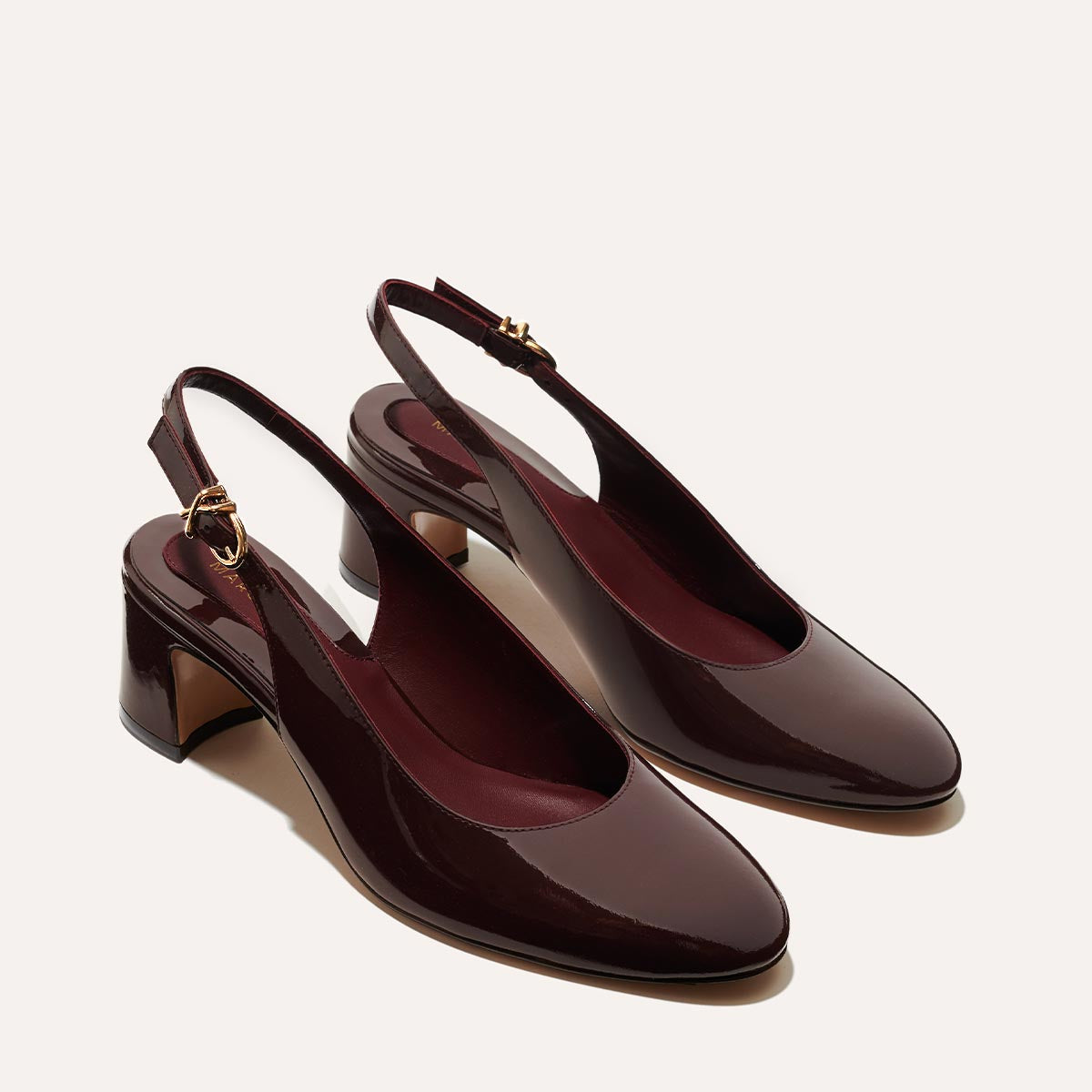 The Cluny Slingback in Burgundy Patent, featuring a sleek Italian nappa leather upper with an adjustable buckle and a comfortable 2.5-inch black heel.