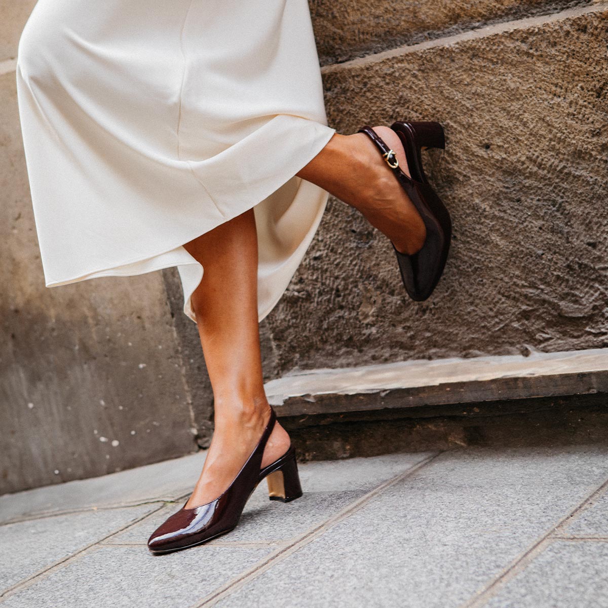 The Cluny Slingback in Burgundy Patent, featuring a sleek Italian nappa leather upper with an adjustable buckle and a comfortable 2.5-inch black heel.