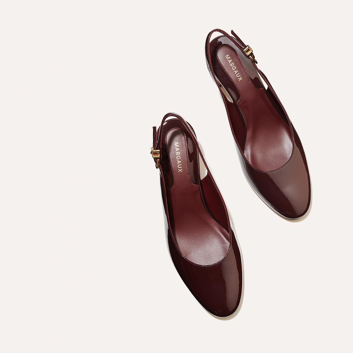 The Cluny Slingback in Burgundy Patent, featuring a sleek Italian nappa leather upper with an adjustable buckle and a comfortable 2.5-inch black heel.