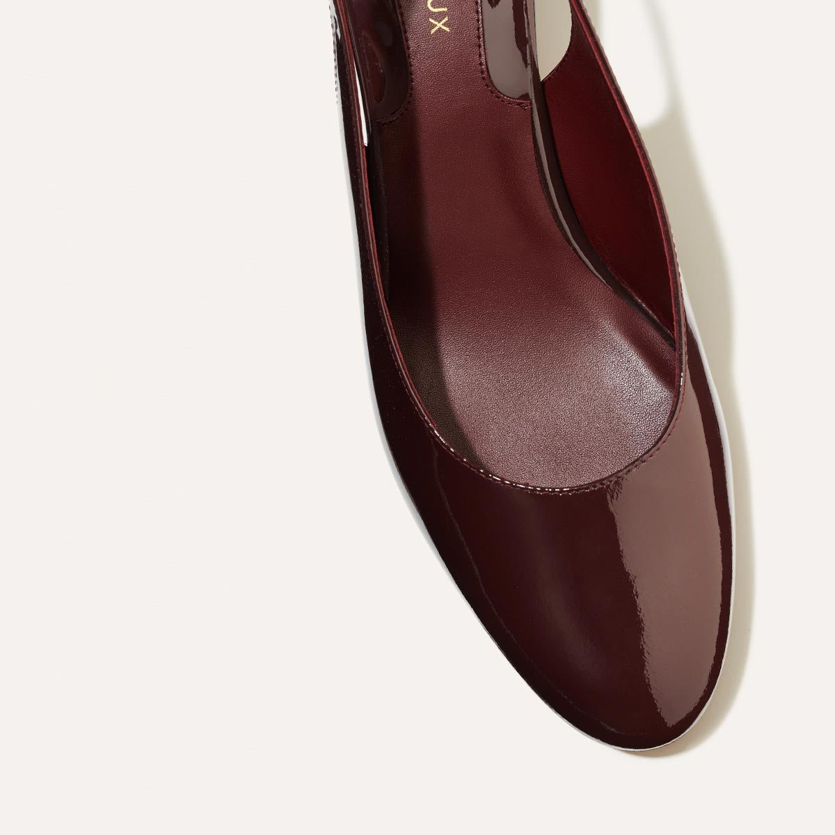 The Cluny Slingback in Burgundy Patent, featuring a sleek Italian nappa leather upper with an adjustable buckle and a comfortable 2.5-inch black heel.