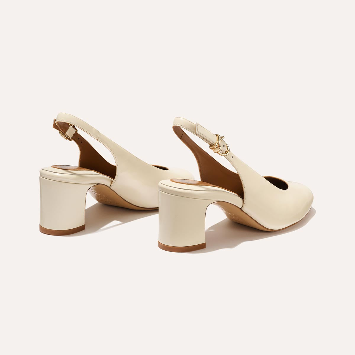 The Cluny Slingback in Cream Nappa, featuring a sleek Italian nappa leather upper with an adjustable buckle and a comfortable 2.5-inch black heel.