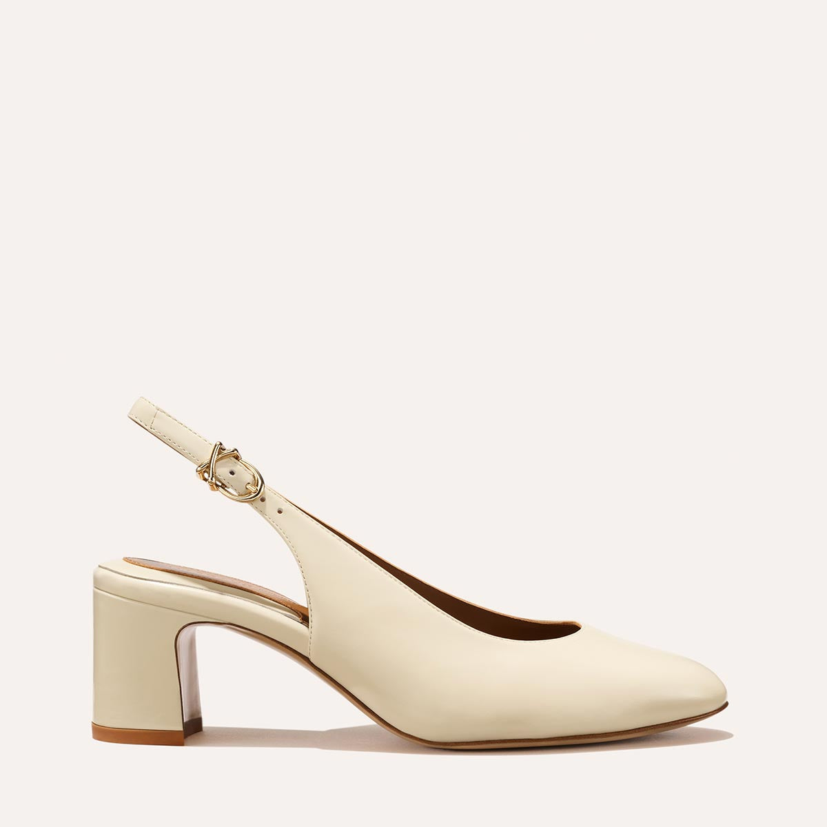 The Cluny Slingback in Cream Nappa, featuring a sleek Italian nappa leather upper with an adjustable buckle and a comfortable 2.5-inch black heel.