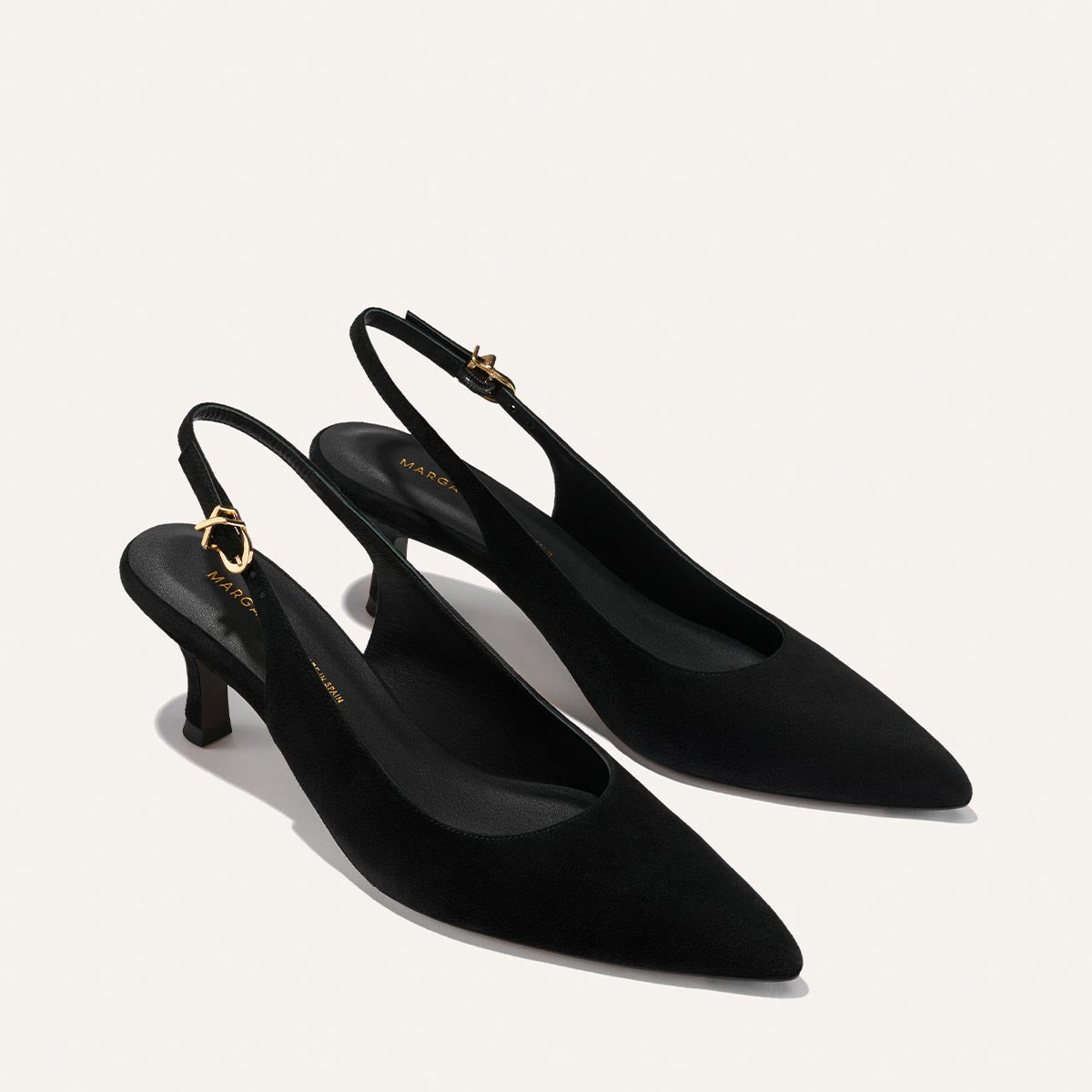 The Colette - Black Suede by Margaux: elegant black suede slingback heels with pointed toes, low kitten heels, and adjustable gold ankle strap buckles, shown on a light background.