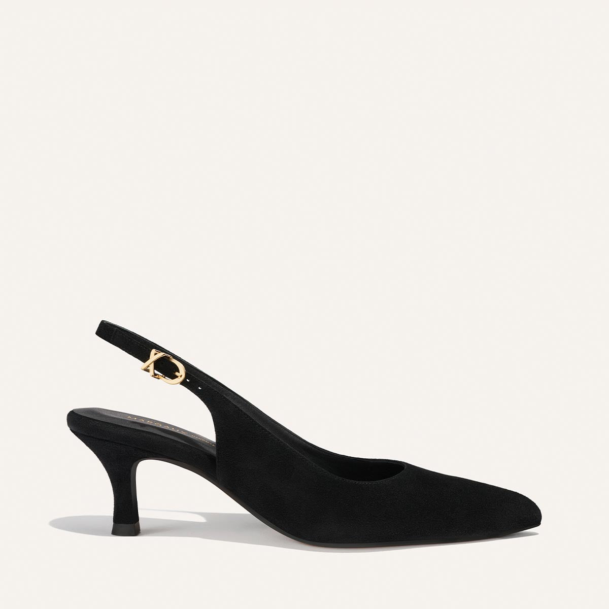 The Colette by Margaux is a black suede slingback heel with a pointed toe, mid-height curved heel, and gold buckle on the ankle strap, shown against a plain white background.