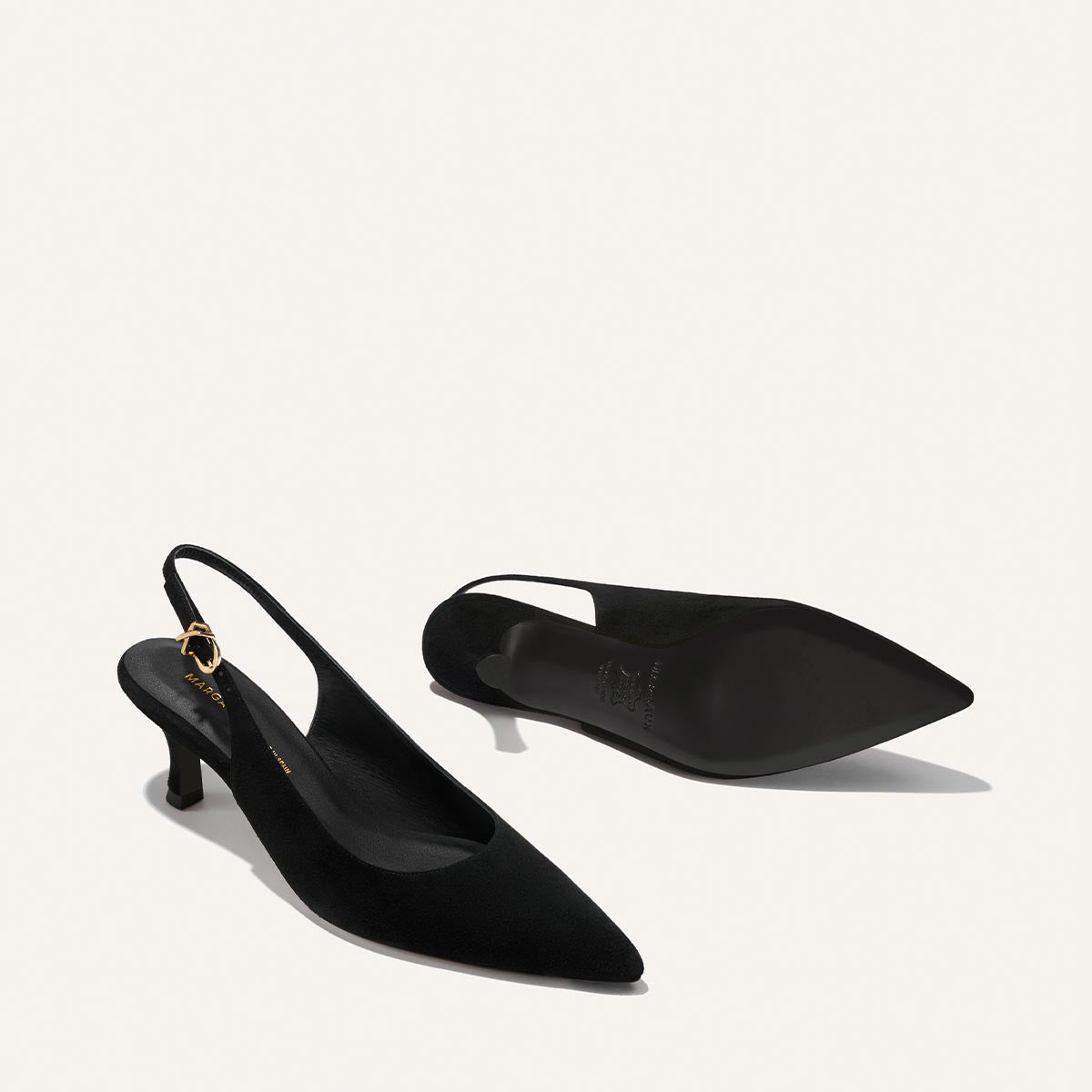 The Colette - Black Suede by Margaux: black suede slingback heels with pointed toes, low kitten heels, and gold buckle ankle straps, shown against a white background.