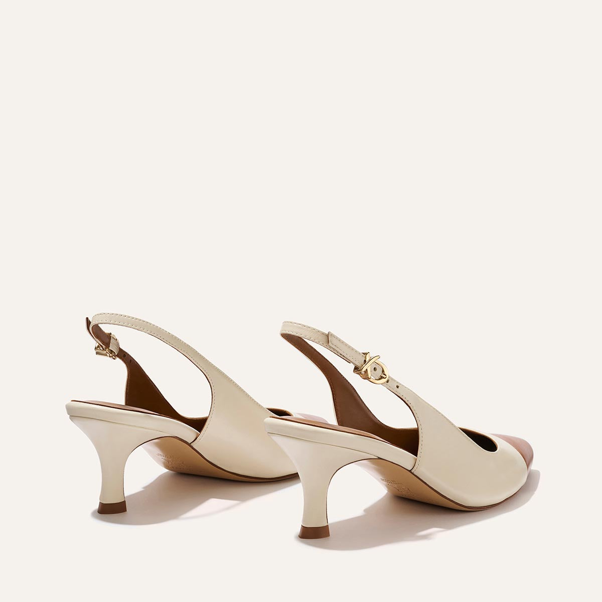 The Colette heels by Margaux feature a cream cotton and saddle nappa finish, chic micro heel, gold buckle strap, and snip nose design, shown against a light background.