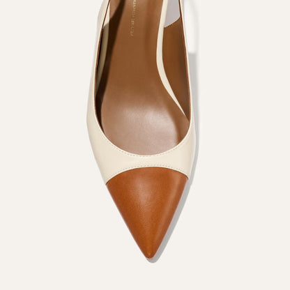 A close-up top view of Margaux's The Colette high heel in Cotton and Saddle Nappa, featuring a pointed snip toe with a tan brown cap and cream sides, set against a plain white background.