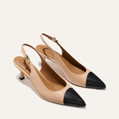 The Colette by Margaux features beige leather, black nappa snip-toe caps, and slim micro heels—elegant slingbacks displayed on a light background.