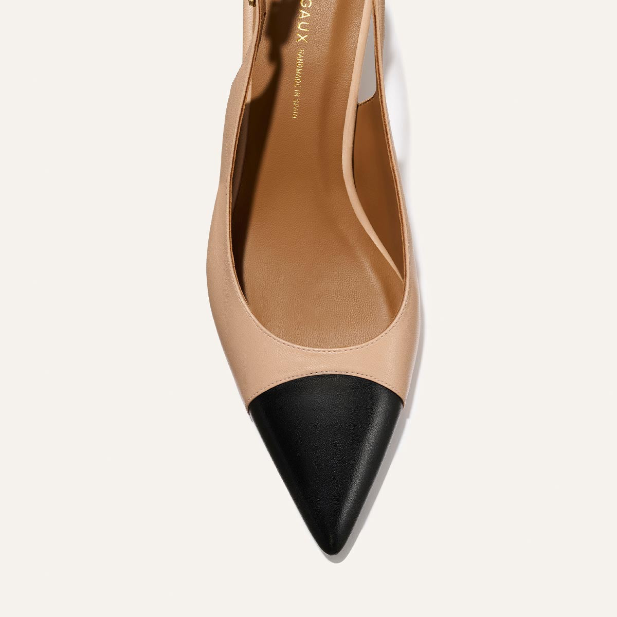 Top view of Margaux's The Colette - Dune and Black Nappa: a women’s pointed-toe slingback with a beige body, black cap toe, and micro heel, set against a light background.