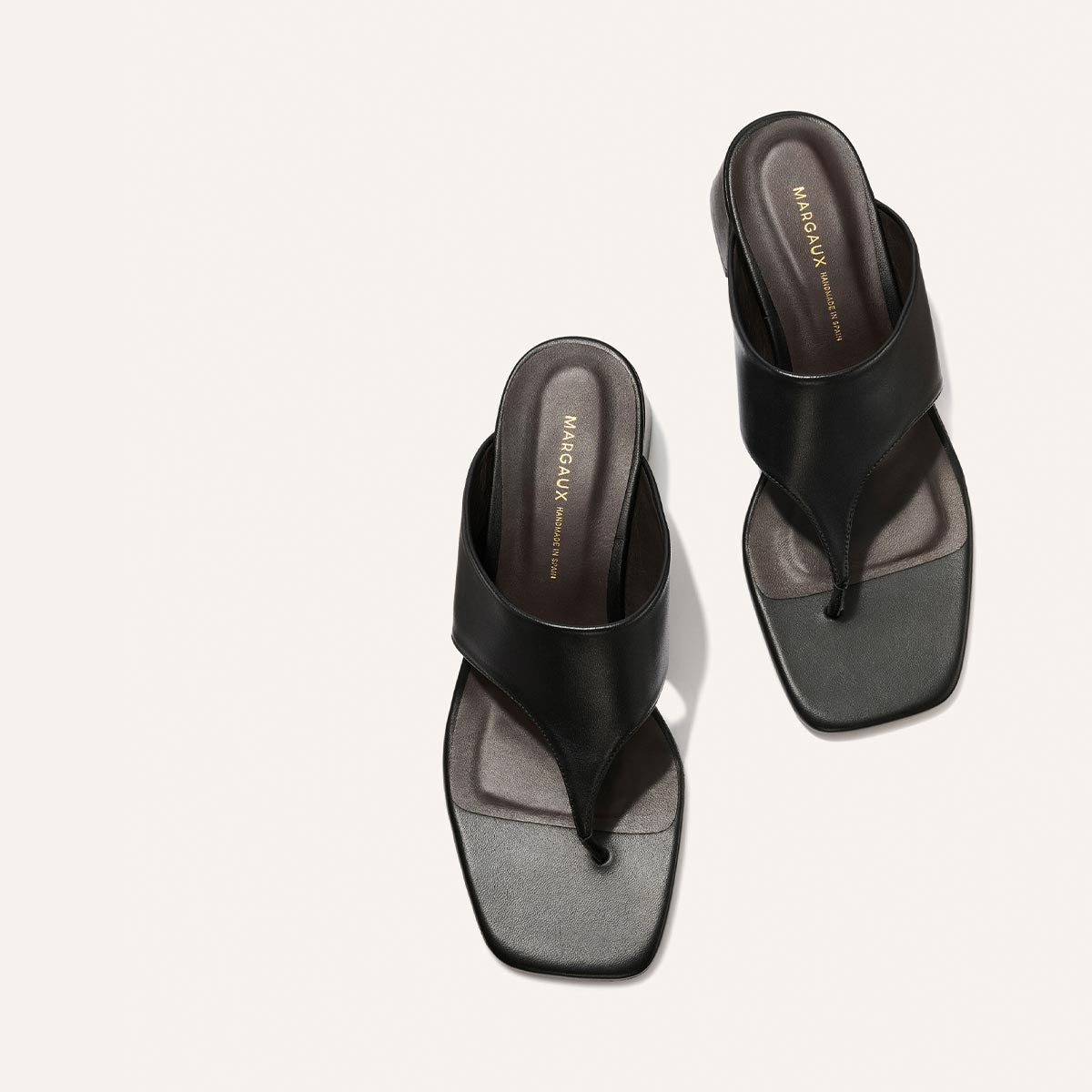 Black and gray sandals with 'Margaux' branding on a white background