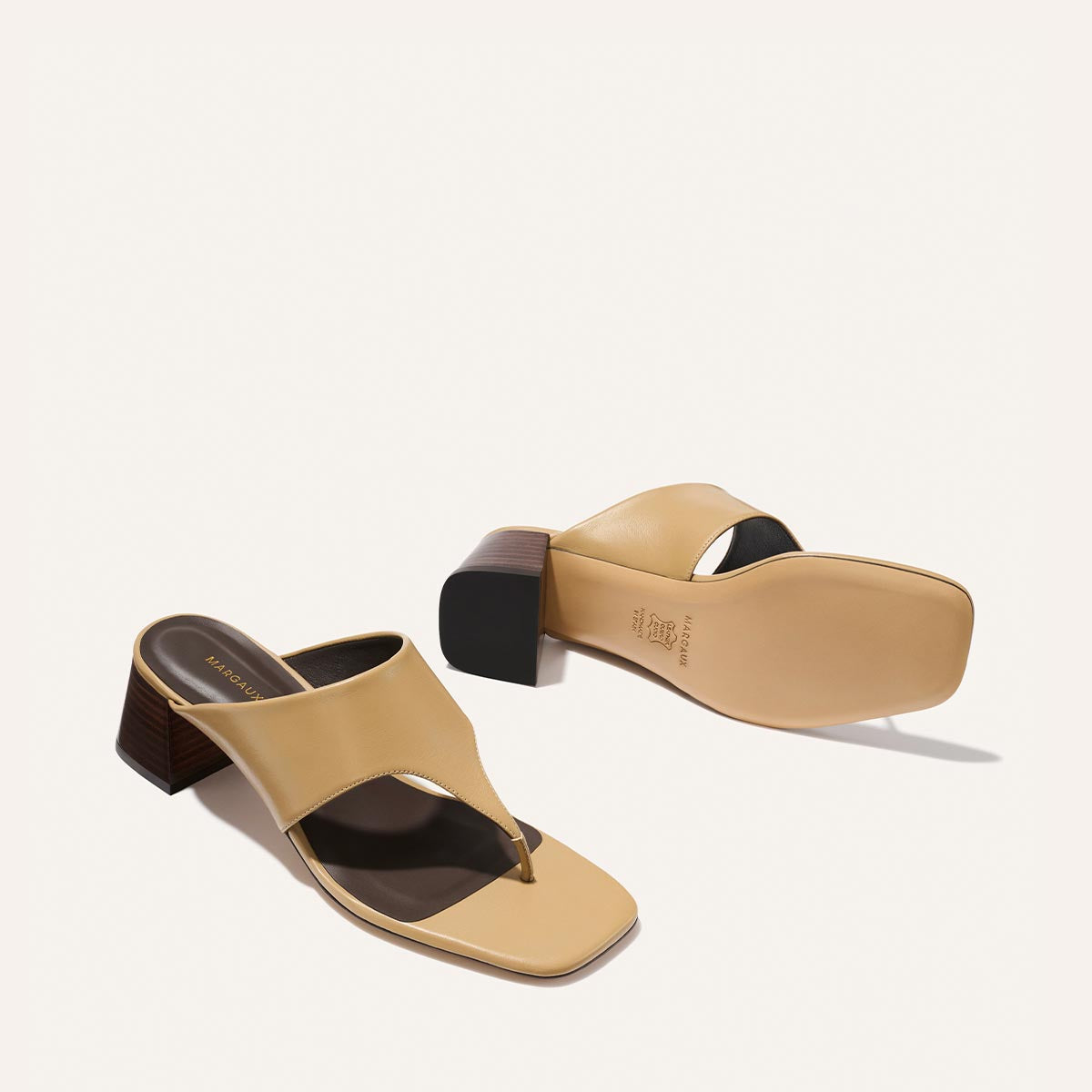 The Deia 50 - Praline Nappa by Margaux: tan heeled sandals with square toes, chunky wooden block heels, and thong-style straps, displayed from top and bottom angles against a plain light background.