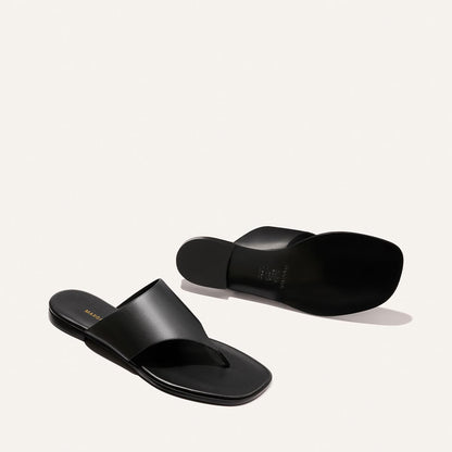 The Deia - Black Nappa by Margaux: a pair of black leather thong sandals with wide straps, one facing up and one down, displayed on a plain white background.