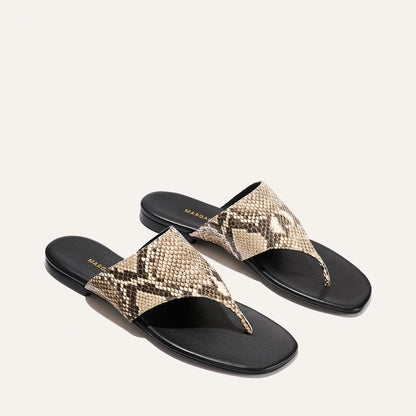 Pair of snake print sandals with black soles on a white background