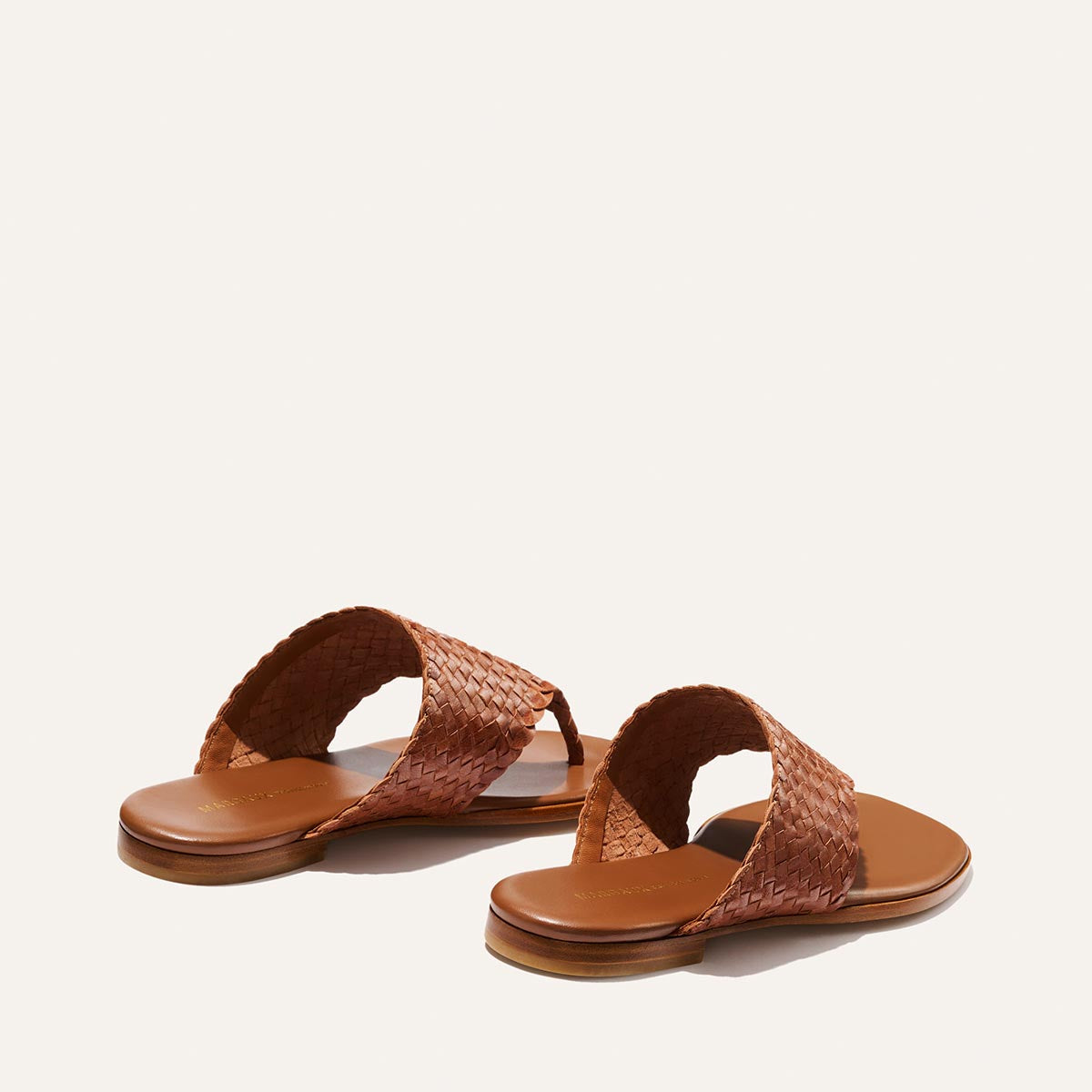 Pair of brown woven sandals on a light beige background