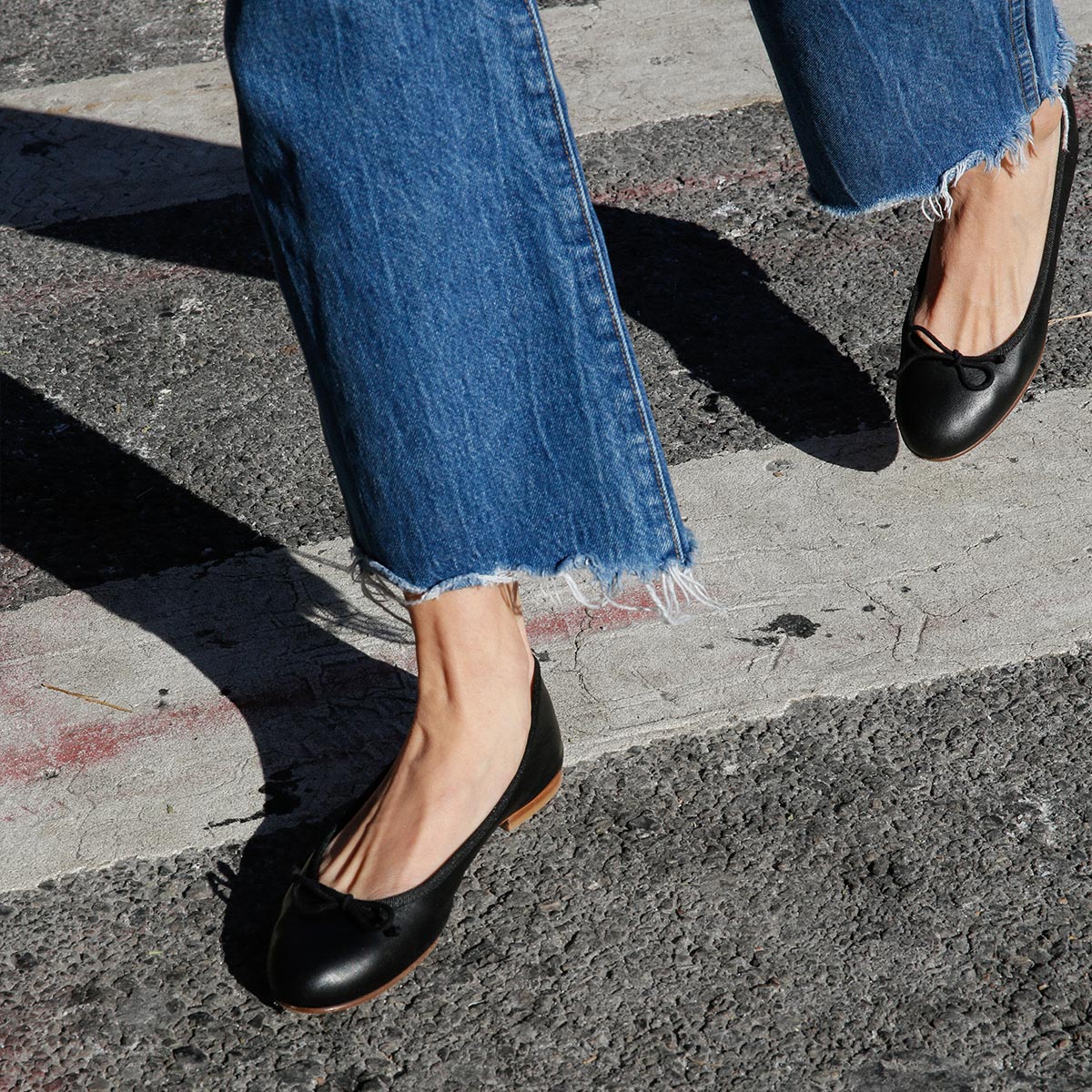 The Demi in Black Nappa, a comfortable ballet flat with a rounded toe and adjustable cord bow detail.