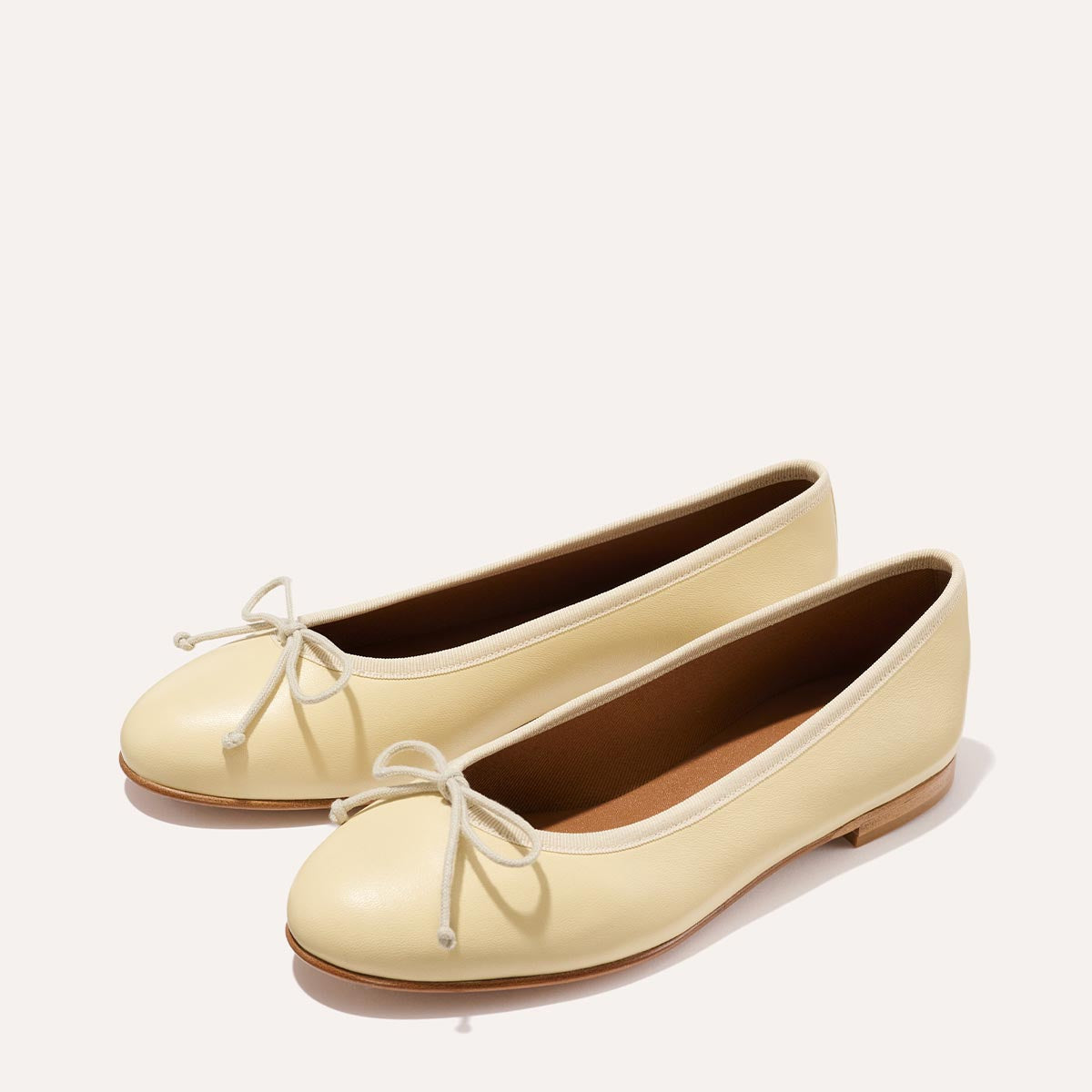 The Demi in light yellow Butter Nappa, a comfortable ballet flat with a rounded toe and adjustable cord bow detail.