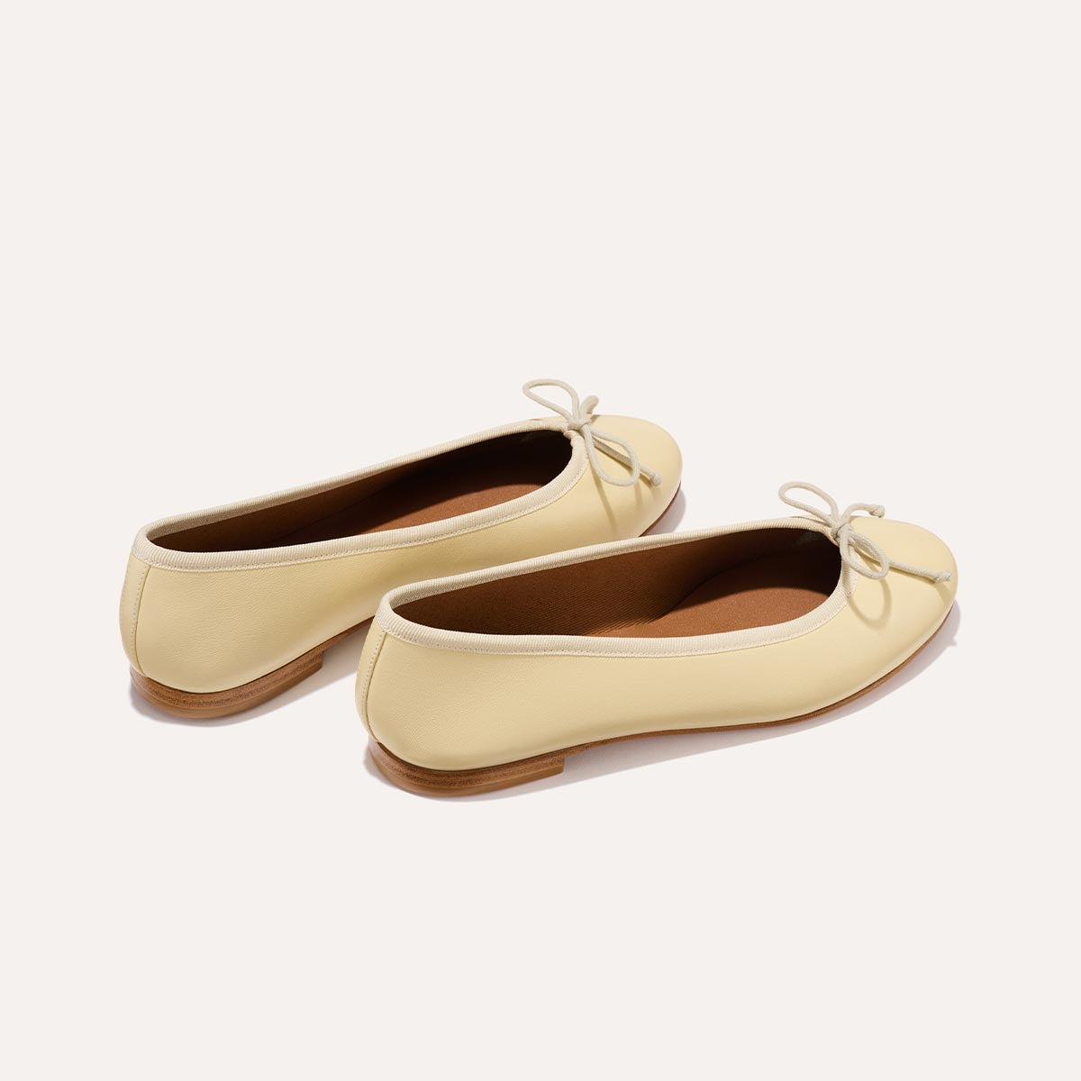 The Demi in light yellow Butter Nappa, a comfortable ballet flat with a rounded toe and adjustable cord bow detail.