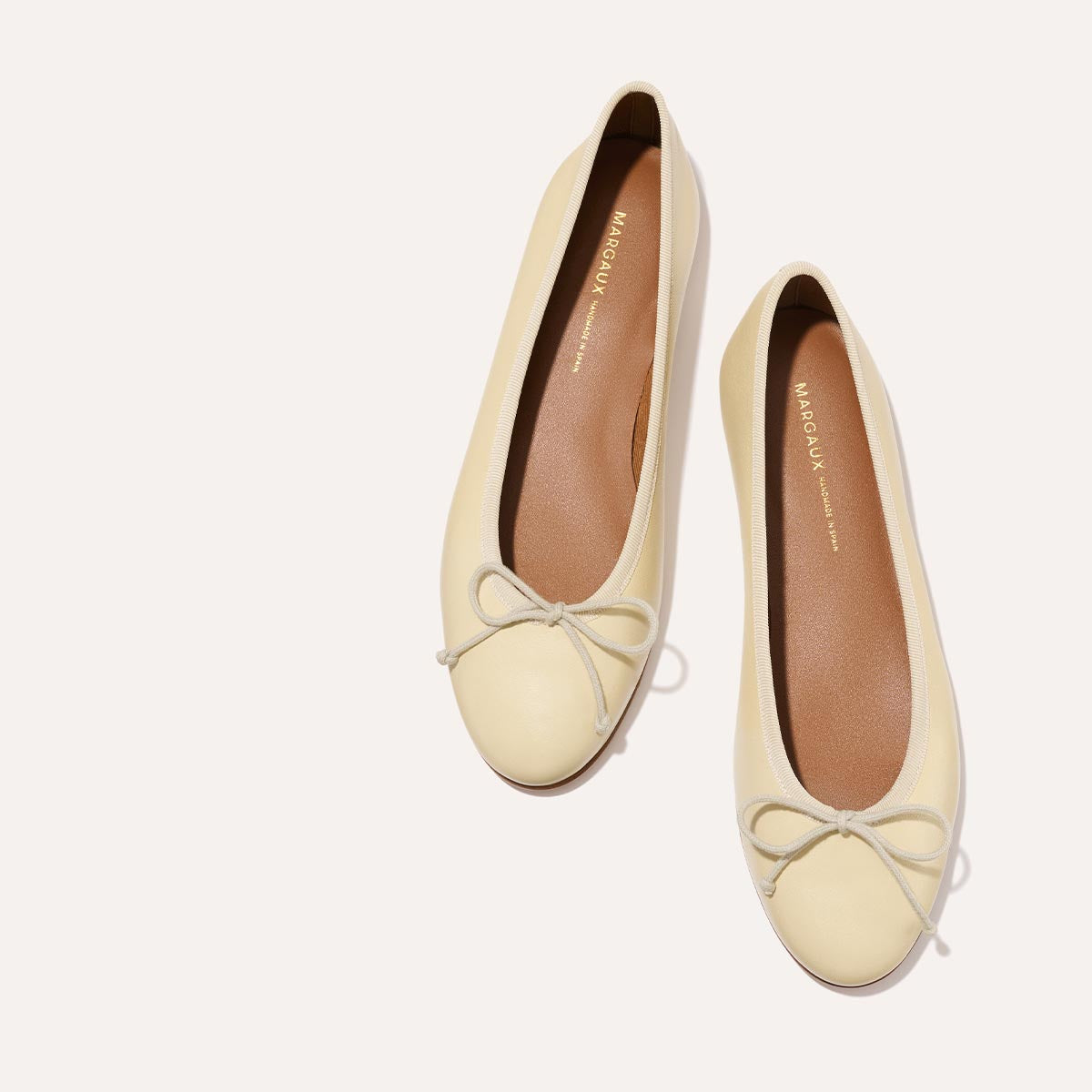 The Demi in light yellow Butter Nappa, a comfortable ballet flat with a rounded toe and adjustable cord bow detail.