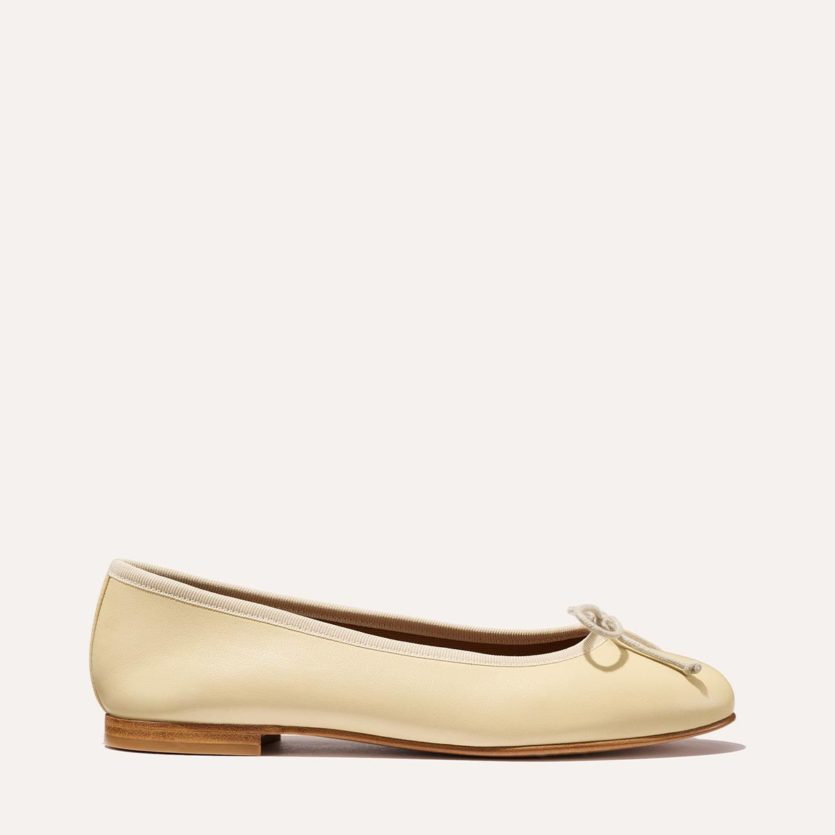 The Demi in light yellow Butter Nappa, a comfortable ballet flat with a rounded toe and adjustable cord bow detail.