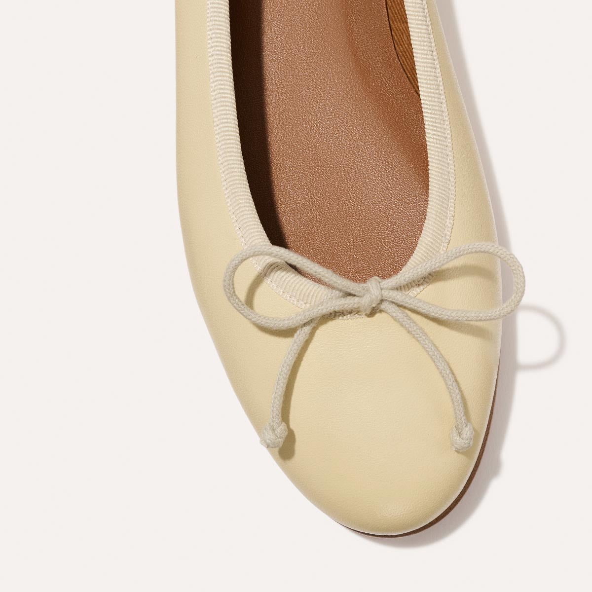 The Demi in light yellow Butter Nappa, a comfortable ballet flat with a rounded toe and adjustable cord bow detail.