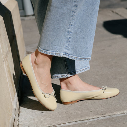 The Demi in light yellow Butter Nappa, a comfortable ballet flat with a rounded toe and adjustable cord bow detail.